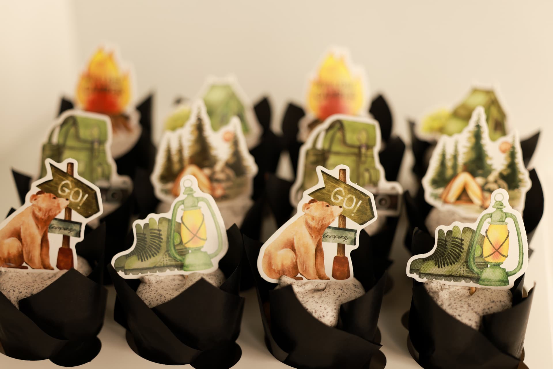 Cupcakes in black tulip wraps with cookies-and-cream frosting and camping-themed toppers